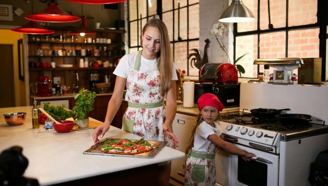 Une mère et sa fille qui vont faire cuire une pizza à la maison